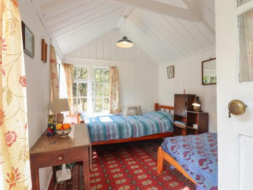 a bedroom with a bed and a desk in a room at Warren Cottage in Leavenheath