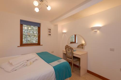 a bedroom with a bed and a desk and a window at White Lodge Apartments in Mawgan Porth