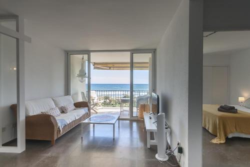 un soggiorno con divano e vista sull'oceano di LETS HOLIDAYS Beach front apartment in Gavà Mar, Pine Beach a Gavà