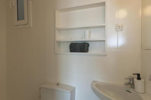 LETS HOLIDAYS Beach front apartment in Gavà Mar, Pine Beach في غافا: حمام أبيض مع حوض ومرحاض