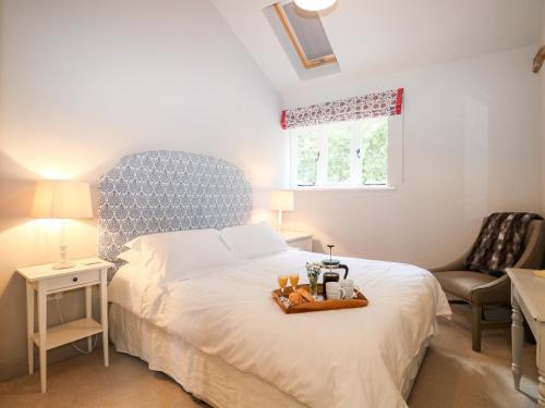 Un dormitorio con una cama con una bandeja de comida. en Barley Cottage en Cheriton