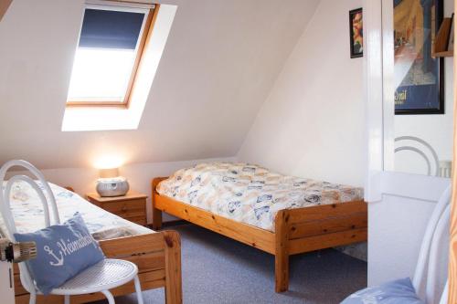 un dormitorio en el ático con 2 camas y una silla en Haus Tjalk Ferienhaus Tjalk rechts, en Norddeich