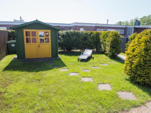 um barracão verde com um banco num quintal em Ferienhaus Albatros em Norddeich