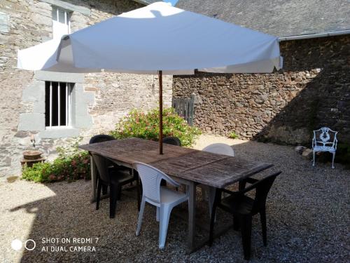 una mesa de madera con una sombrilla en el patio en Teag Beag, en La Grée-Saint-Laurent