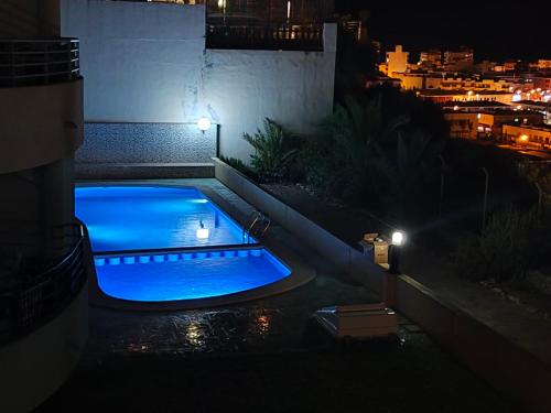 a blue swimming pool in a backyard at night at Apartamento en Puerto de Mazarrón in Puerto de Mazarrón