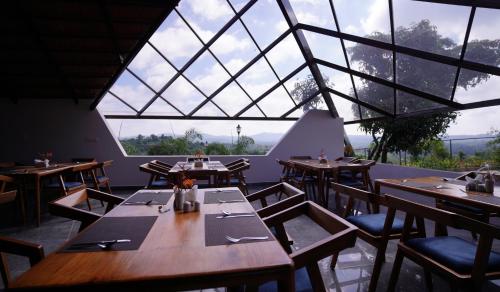 a restaurant with wooden tables and chairs and a large window at Ravishing Retreat Resort in Rāmanagaram