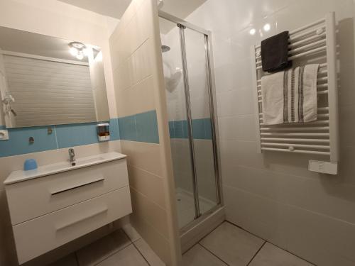 uma casa de banho branca com um chuveiro e um lavatório. em studio 2 personnes entre terre et mer em Questembert