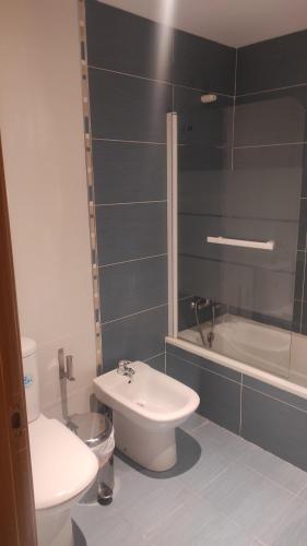 a bathroom with a toilet and a sink and a tub at Apartamento Nicomar in Escarrilla