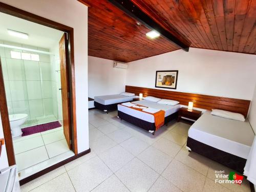 a room with two beds and a bathroom with a shower at Hotel Villar in Penedo