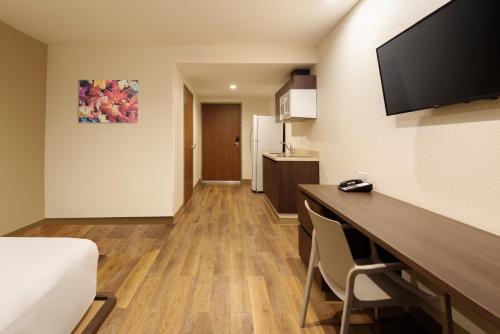 a room with a bed and a desk with a television at Extended Suites Mexicali Catavina in Mexicali