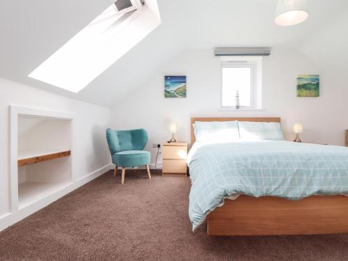 a bedroom with a bed and a blue chair at Atlantic Reach in Marazion