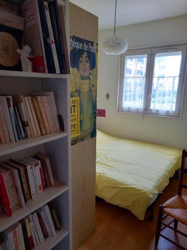 - une chambre avec un lit et une étagère avec des livres dans l'établissement Appartement charmant avec vue sur la mer à Cabourg - 30 m², à Cabourg