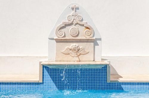 a fountain in a swimming pool next to a swimming pool at Páteo dos Oliveira - Casa dos Senhores in Évora