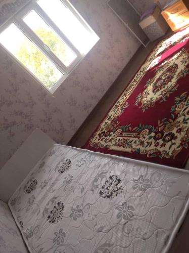 a bedroom with a bed and a window and a bedspread at "Kamchybek Ata" guest house B&B in Tërt-Kul'