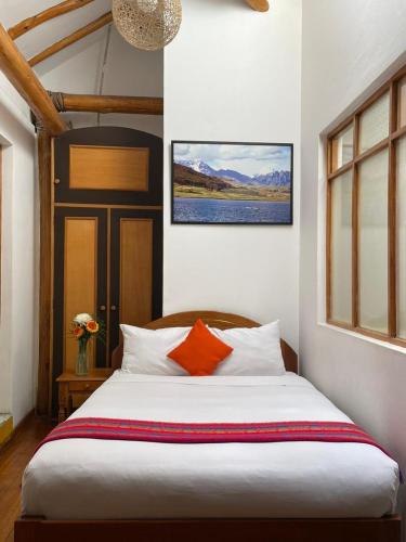 a bedroom with a large white bed with orange pillows at Hotel Monasterio San Pedro in Cusco