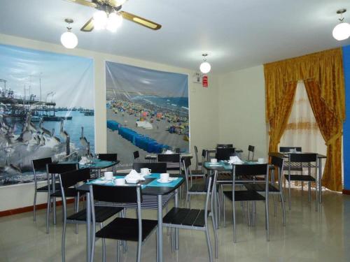 a dining room with tables and chairs and a large painting at Hostal Puerto Ingles in Ilo