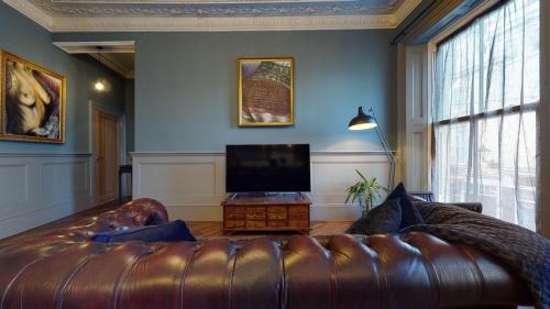 a living room with a leather couch and a flat screen tv at Barbican Boutique Luxury Apartments & Rooms, Plymouth in Plymouth