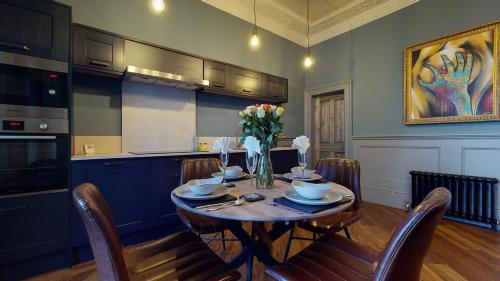 a dining room with a table with chairs and flowers at Barbican Boutique Luxury Apartments & Rooms, Plymouth in Plymouth