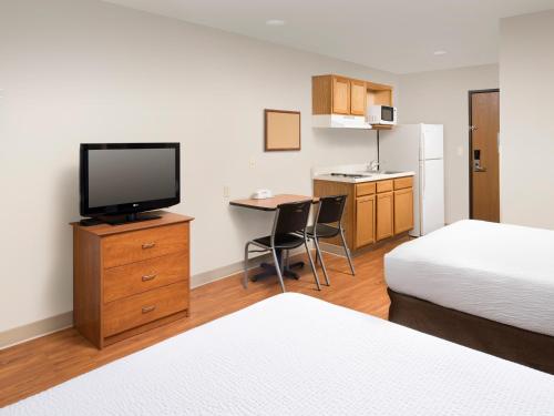 a hotel room with a television and a desk with a bed at Studio 6 Extended Stay Wichita South KS in Wichita