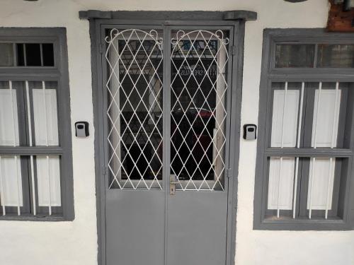 a white door with a wrought iron gate next to two windows at Hutton Lane Hostel Georgetown in George Town