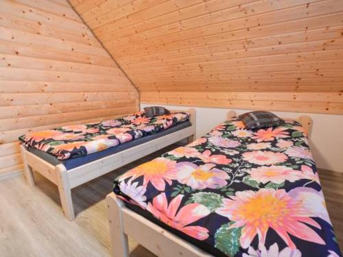 2 łóżka w pokoju z drewnianymi ścianami w obiekcie Domki w Bieszczadzkiej Dolinie w mieście Ustrzyki Dolne