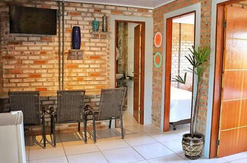 Habitación con mesa, sillas y pared de ladrillo. en Pousada Moçamba Dunas Beach, en Florianópolis