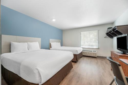 a hotel room with a large bed and a flat screen tv at Extended Stay America Select Suites - Orlando - East in Orlando