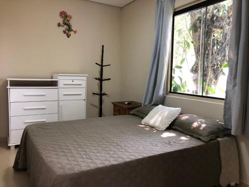um quarto com uma cama e uma janela grande em Pousada Ondas de Floripa em Florianópolis