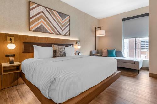 a bedroom with a large white bed and a couch at Cambria Hotel Columbia Downtown the Vista in Columbia