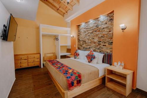 a bedroom with a large bed and a brick wall at Hotel Cielo y Selva, San Cristobal de las Casas in San Cristóbal de Las Casas