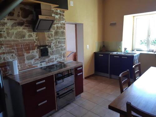a kitchen with a sink and a stove top oven at Ferme O'Clés in Le Peuchapatte