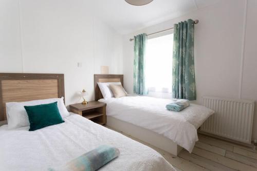 a bedroom with two beds and a window at Spacious Homely Lakeside Lodge close to the Beaches in Chichester