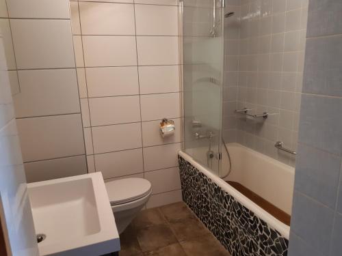 a bathroom with a toilet and a tub and a sink at Ferme O'Clés in Le Peuchapatte