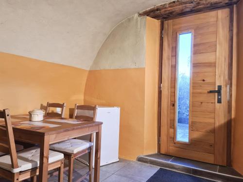 a dining room with a wooden table and a door at Ferme O'Clés in Le Peuchapatte