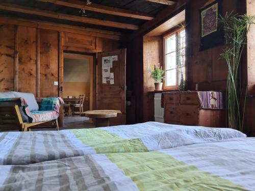 a bedroom with a bed and a chair and a table at Ferme O'Clés in Le Peuchapatte