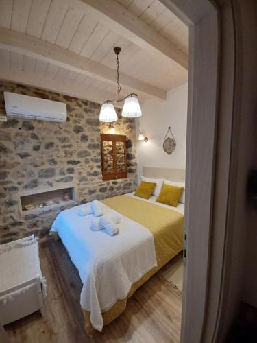 a bedroom with a bed and a stone wall at Rodanthe's Guest House in Stemnitsa