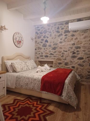 a bedroom with a bed and a stone wall at Rodanthe's Guest House in Stemnitsa