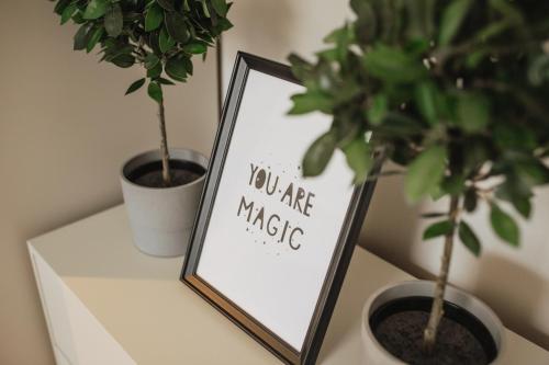 a sign on a shelf next to two potted plants at Rozenstein design residence in Brocēni