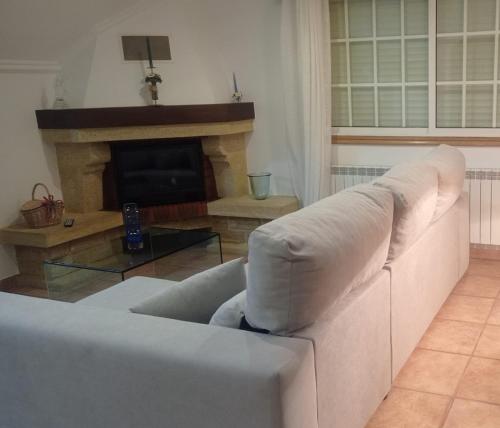 un sofá blanco en una sala de estar con chimenea en A Morada de Julia, Acogedor apartamento en el balcón del Valle Miñor, en Pontevedra
