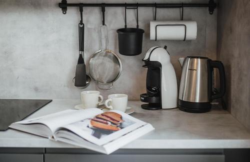 un mostrador de cocina con un libro y un sándwich y tazas en Rozenstein design residence en Brocēni