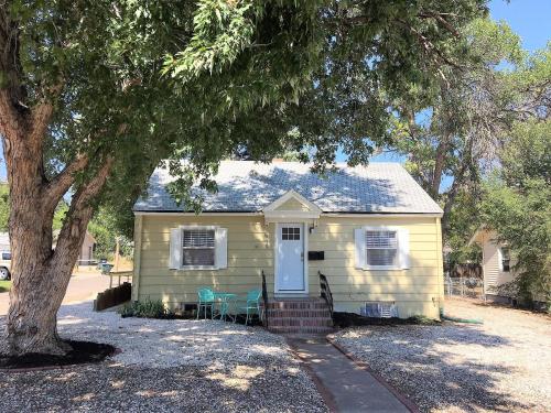 a yellow house with two chairs and a tree at Close to UNC with Great Yard, Firepit & Free Bikes! in Greeley