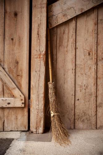 a broom leaning against a wooden wall at Ferme O'Clés in Le Peuchapatte