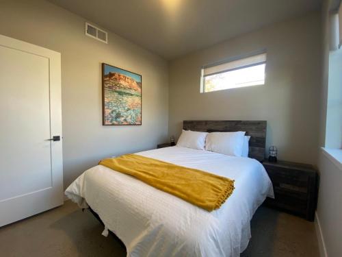 Un dormitorio con una cama con una manta amarilla. en Old Town Modern New Build - Rooftop Spa with Mtn Views!, en Fort Collins