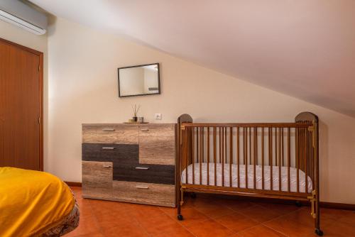 a bedroom with a crib and a dresser with a mirror at CASA POR DO SOL in Calheta