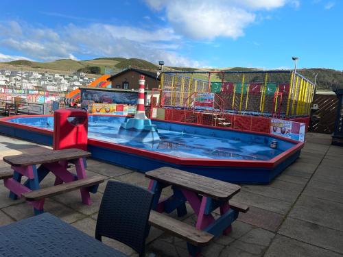 a large swimming pool with two tables and two benches at Beautiful 2-Bed Chalet in Aberystwyth in Aberystwyth