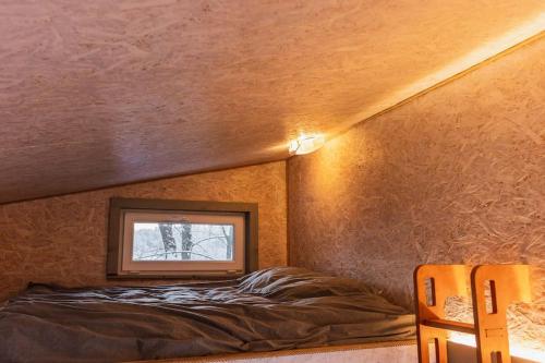 ein kleines Bett in einem Zimmer mit Fenster in der Unterkunft Beautiful Tiny house on the lake side. in Trakai