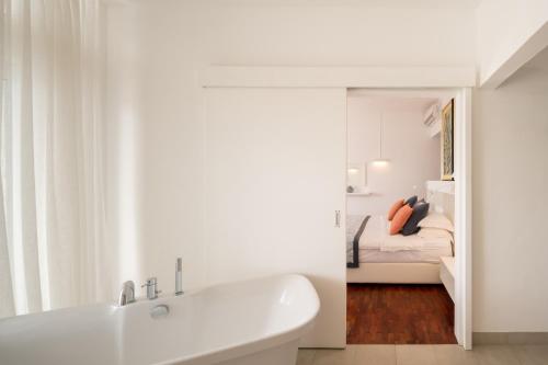 a white bathroom with a tub and a bedroom at Villa Cambier by muse villas in Le Morne
