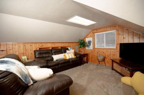 a living room with a leather couch and a television at Afton Farmhouse with Mountain Views in Afton