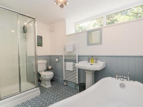 a bathroom with a tub and a toilet and a sink at Caldhu Cottage in Holmrook