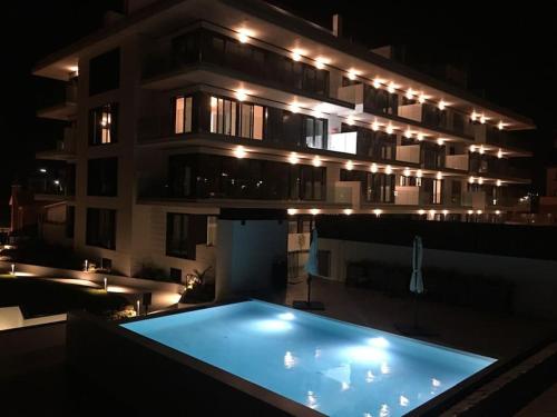 ein Apartmenthaus mit Pool in der Nacht in der Unterkunft Apartamento en Edificio Nuevo con Piscina in Portonovo